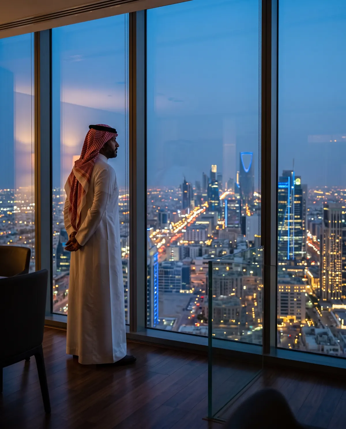 Saudi executive looking over the Riyadh skyline from an office tower at dusk